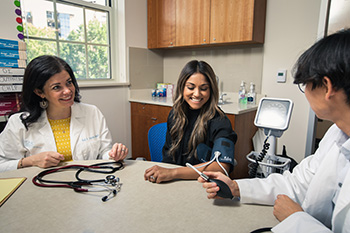 Doctors sitting at a table with a patient checking her blood pressure