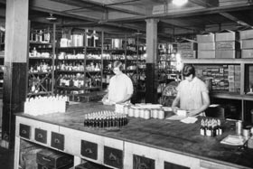 In a historical photo from 1833, two women stand behind a pharmacy counter