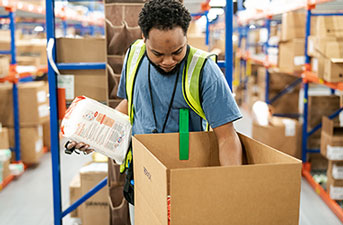 distribution center packing a box with supplies