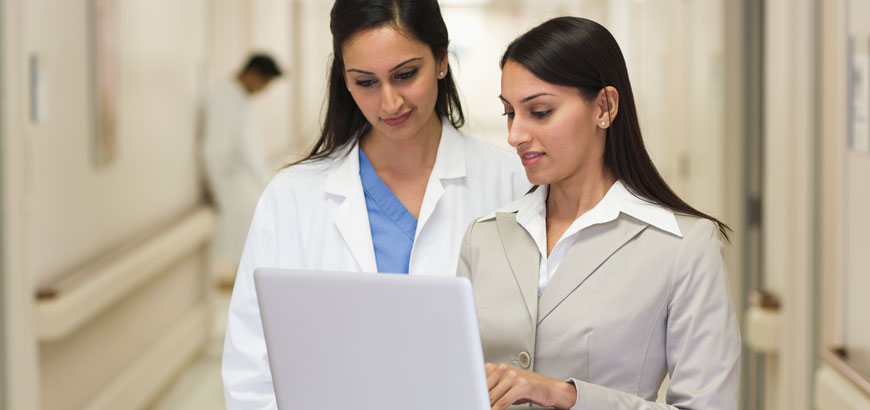 <span>Businesswoman showing laptop to doctor in hospital</span>