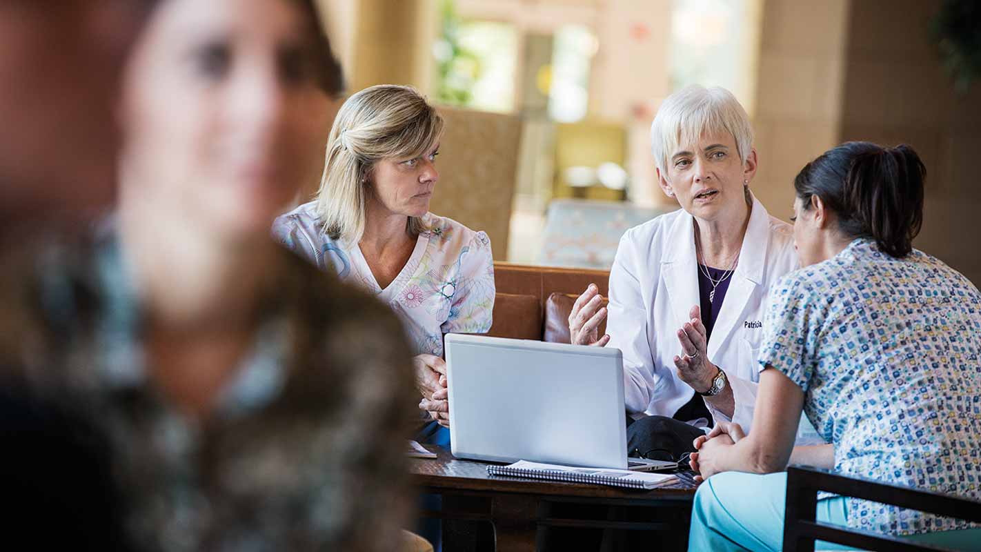 A doctor meeting with two nurses in a hospital lobby