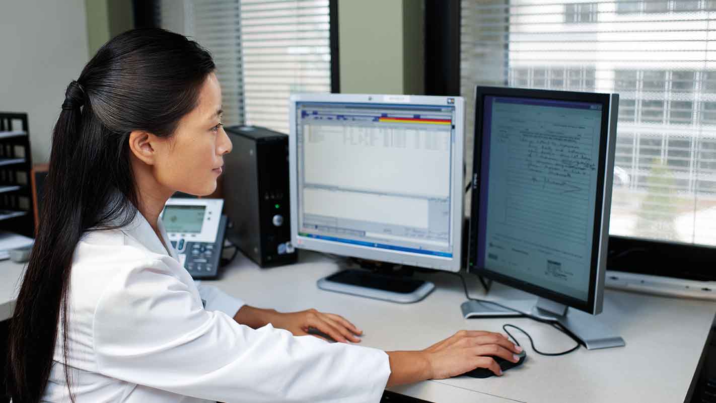 A pharmacist views a prescription on a computer screen.