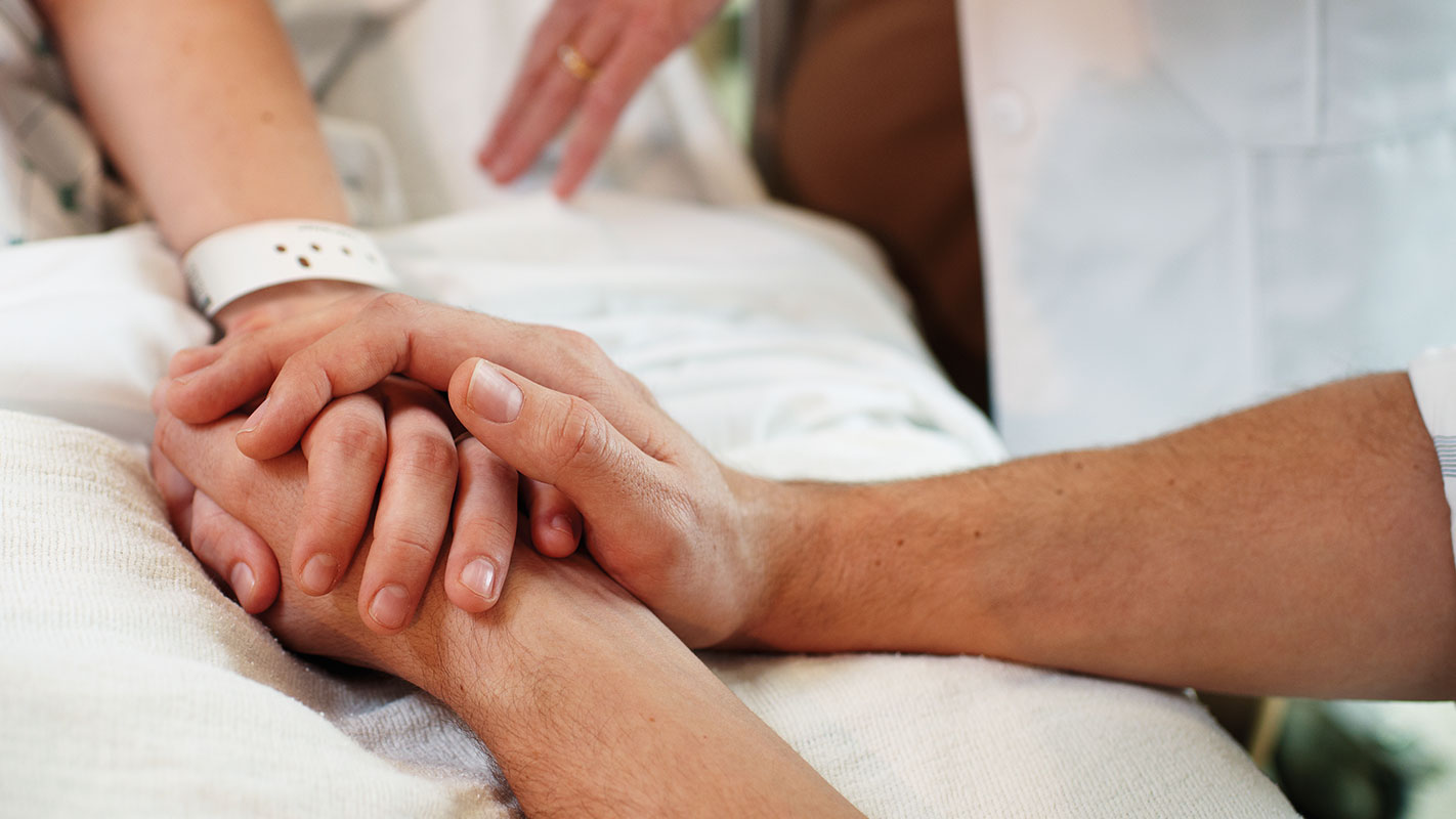 Close up of a patient's hand being held.