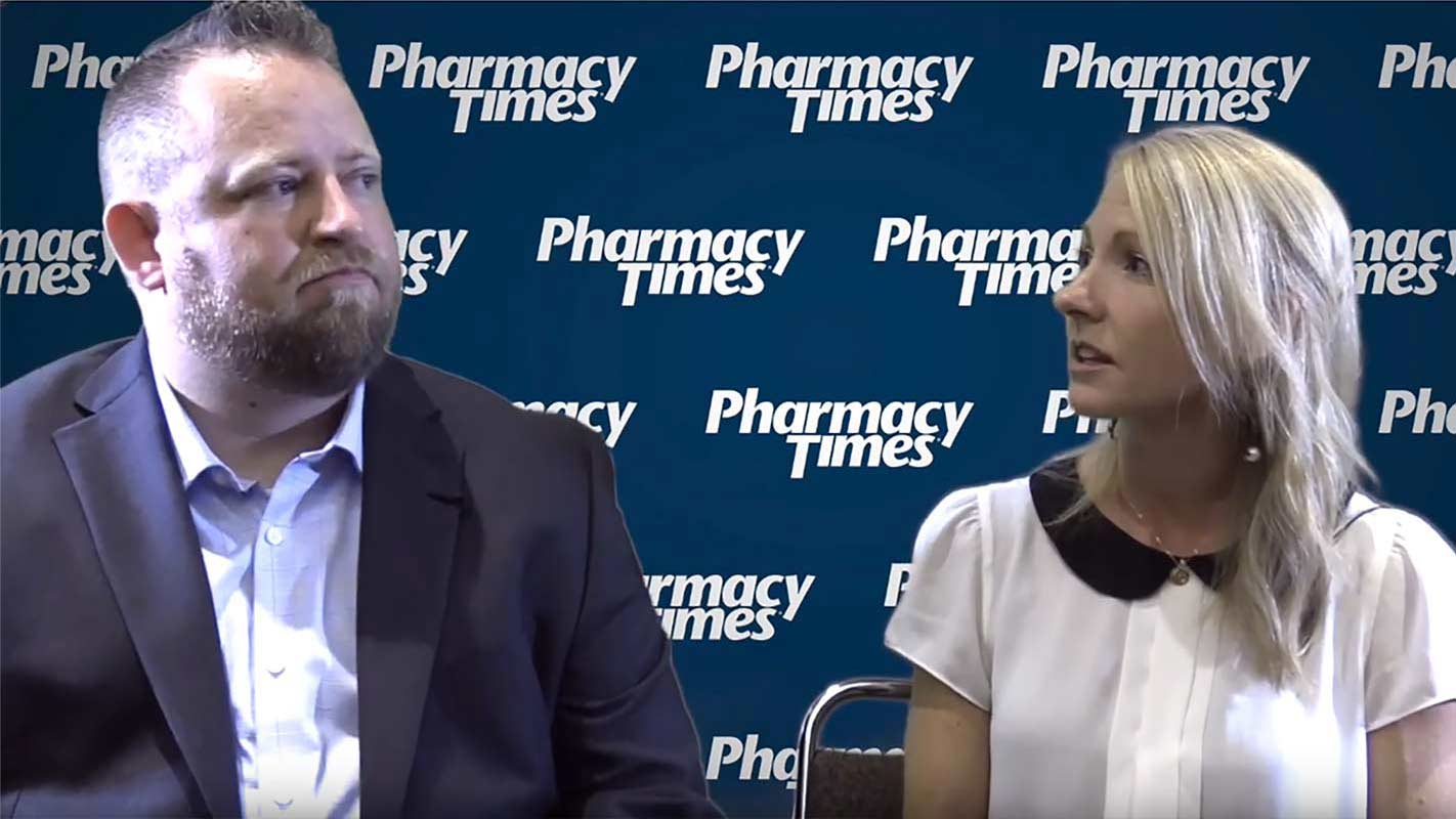 Two people giving an interview in front of a Pharmacy Times backdrop