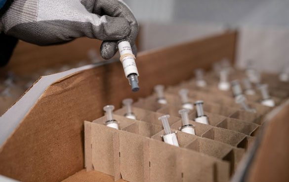 Close up of a gloved hand pulling vials out of a box