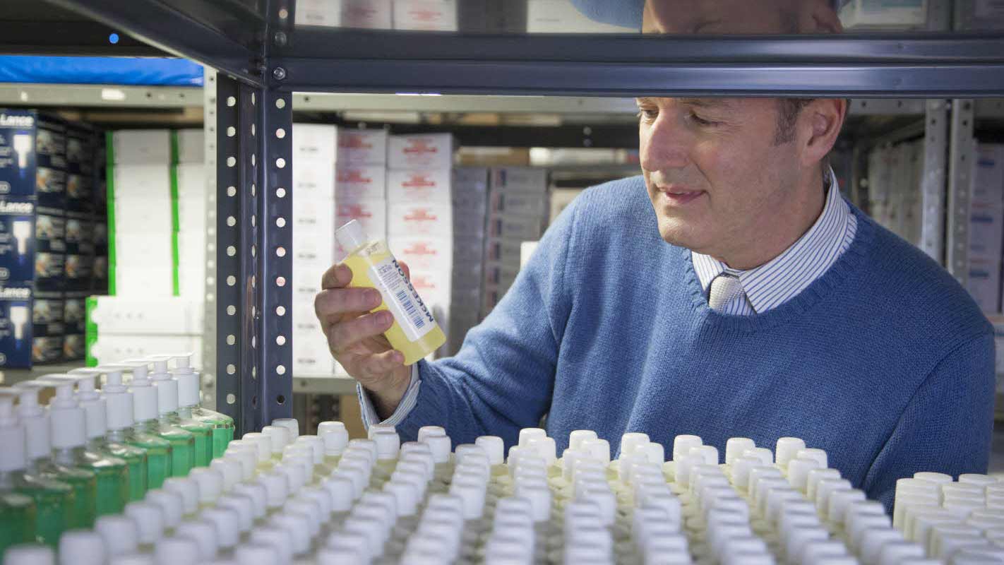 A man in a warehouse looks at a McKesson medicine bottle