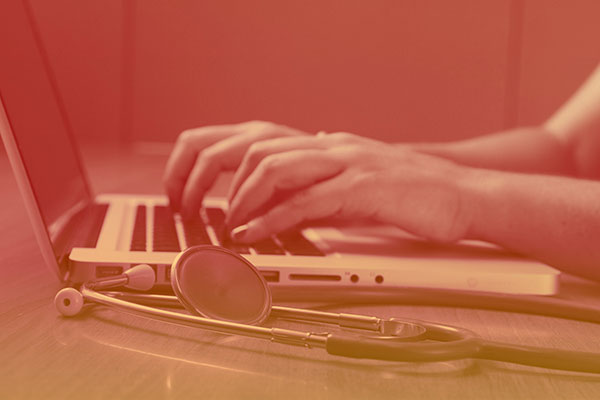 An image of a doctor's hands charting on a computer