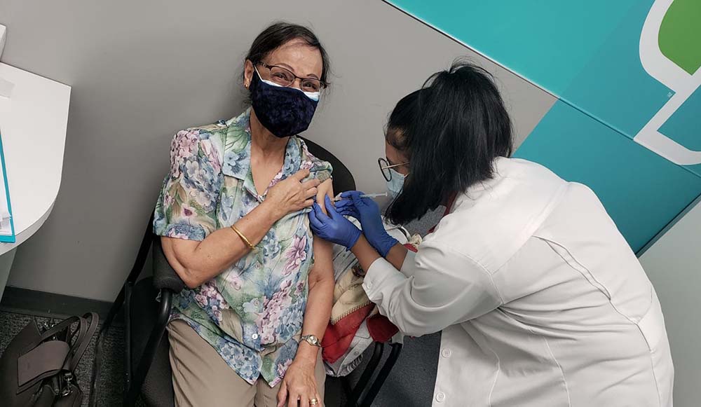 A pharmacist at a Rexall pharmacy in Calgary, Alberta administers a dose of COVID-19 vaccine into the arm of a patient.