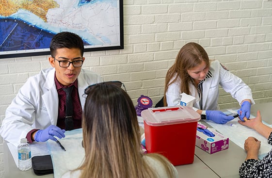 Two healthcare workers taking people's blood samples