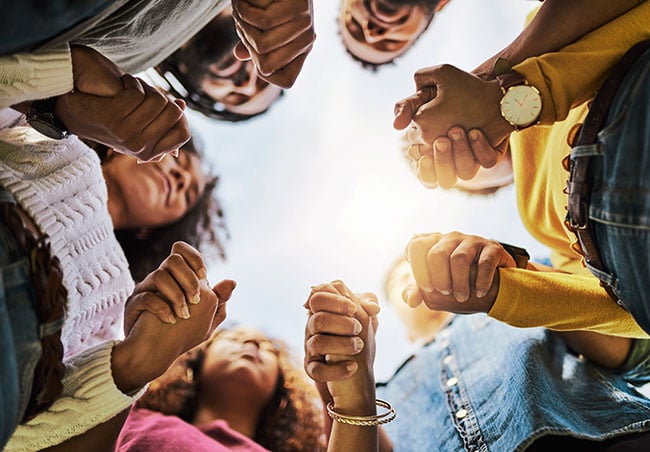 A group of people standing in a circle and holding hands.