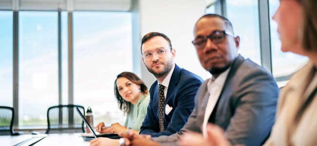 People sit next to each other at an office conference table<br>  