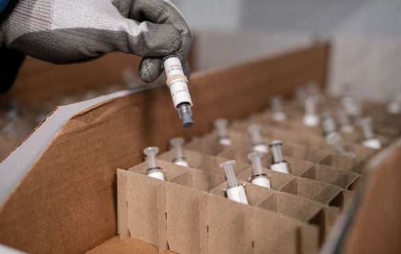 Close up of a gloved hand pulling vials out of a box