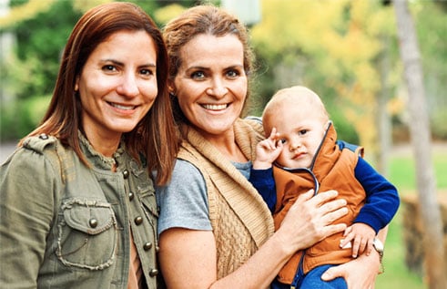 Two women stand together and hold a baby