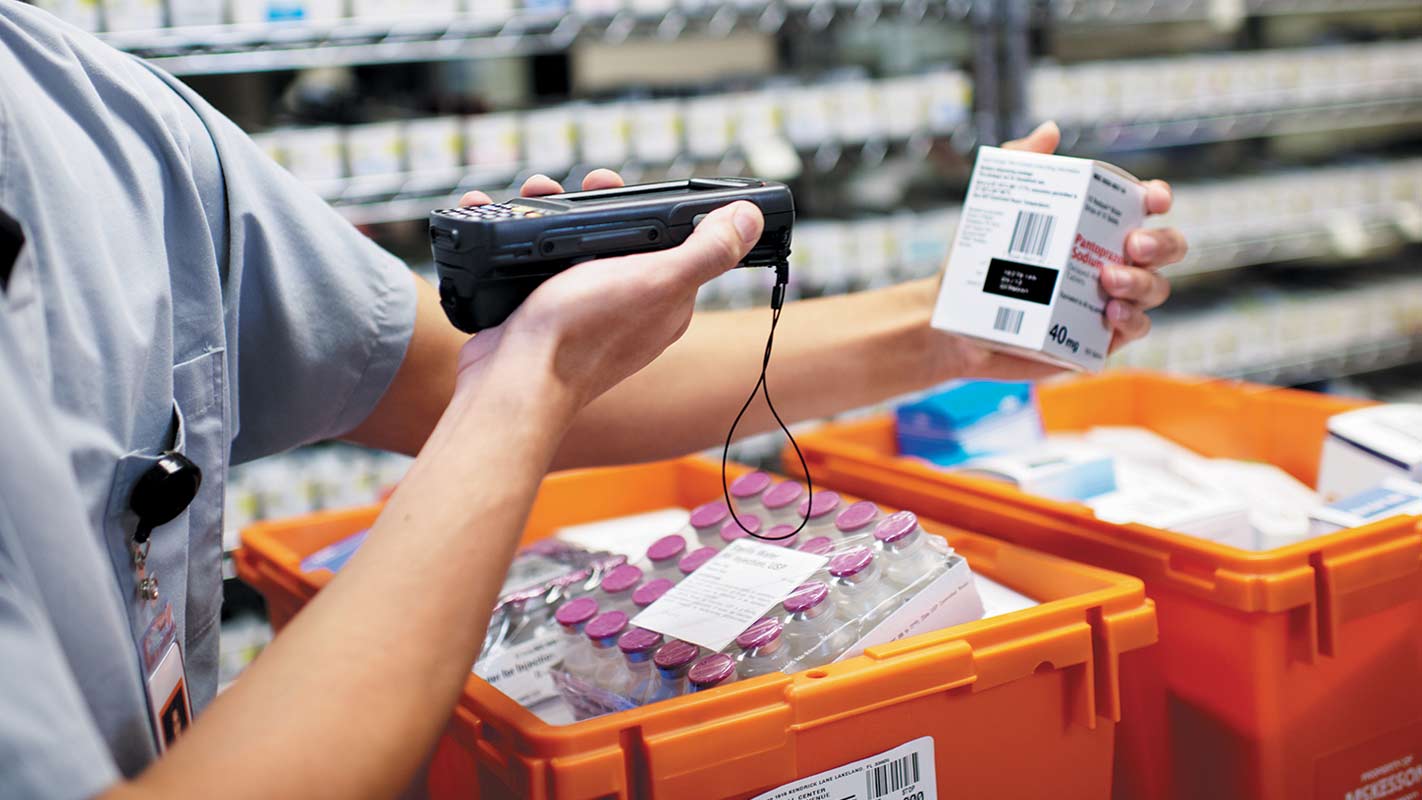 Health care worker using a handheld scanner to scan a box of medication<br>  