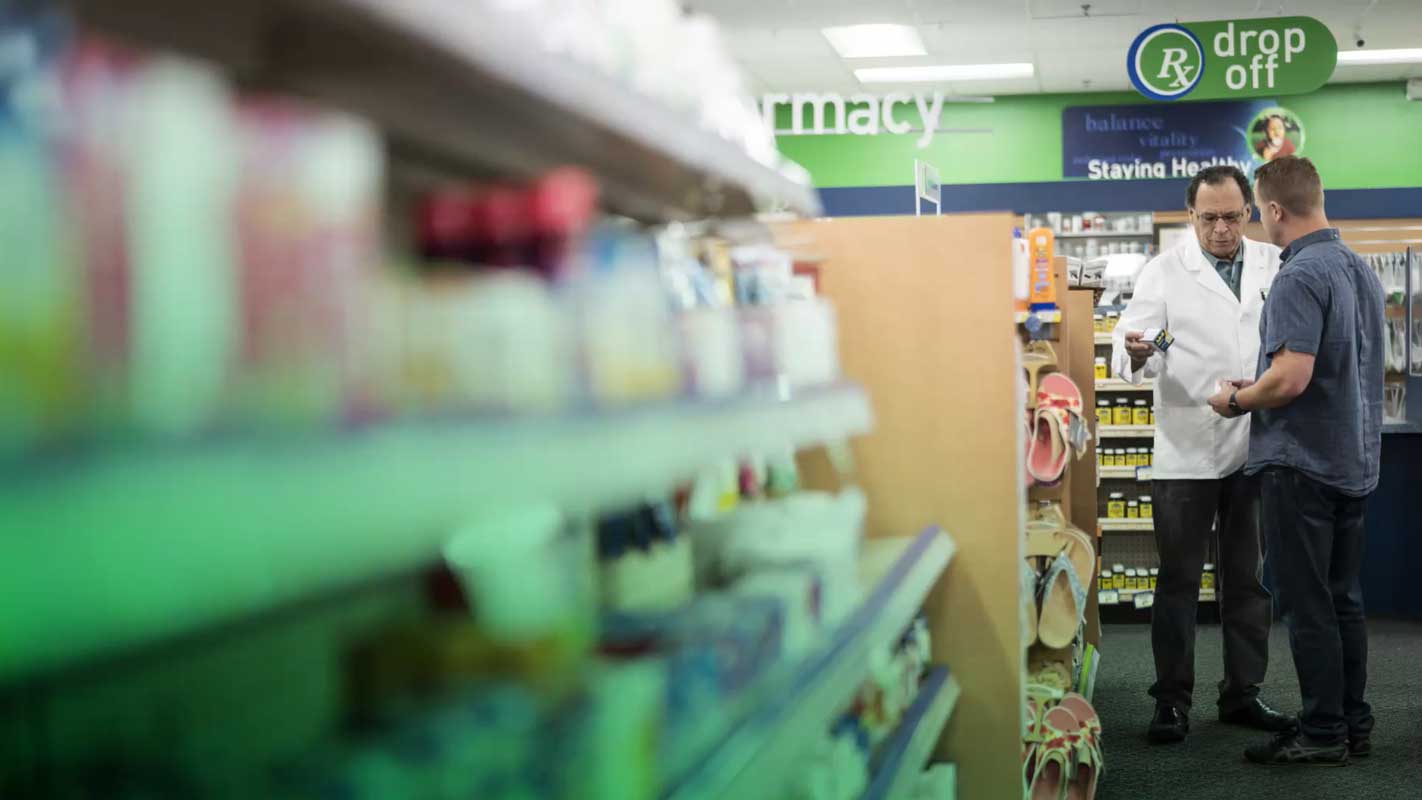 A pharmacist and a patient talking to each other in a retail pharmacy