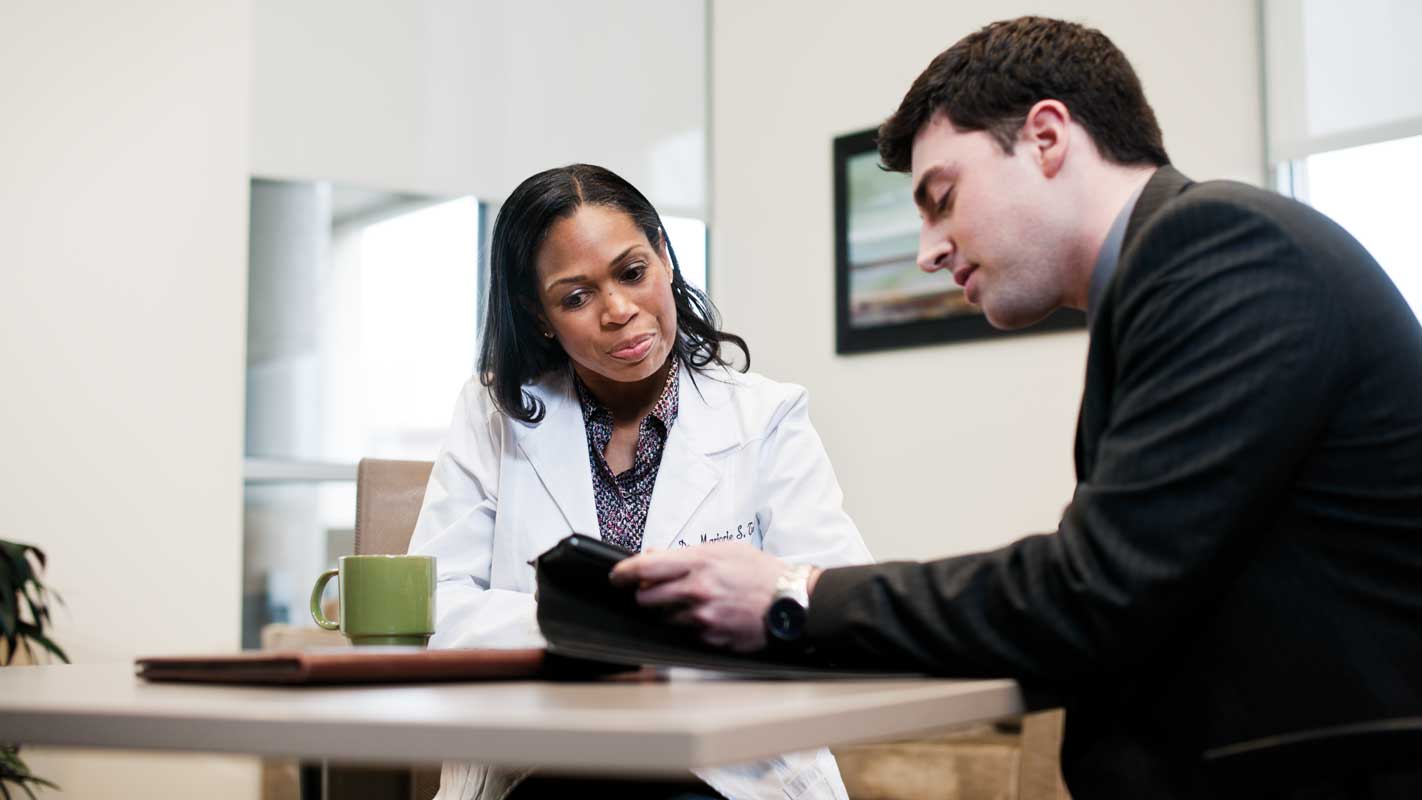 A doctor sitting at a table talking to a patient