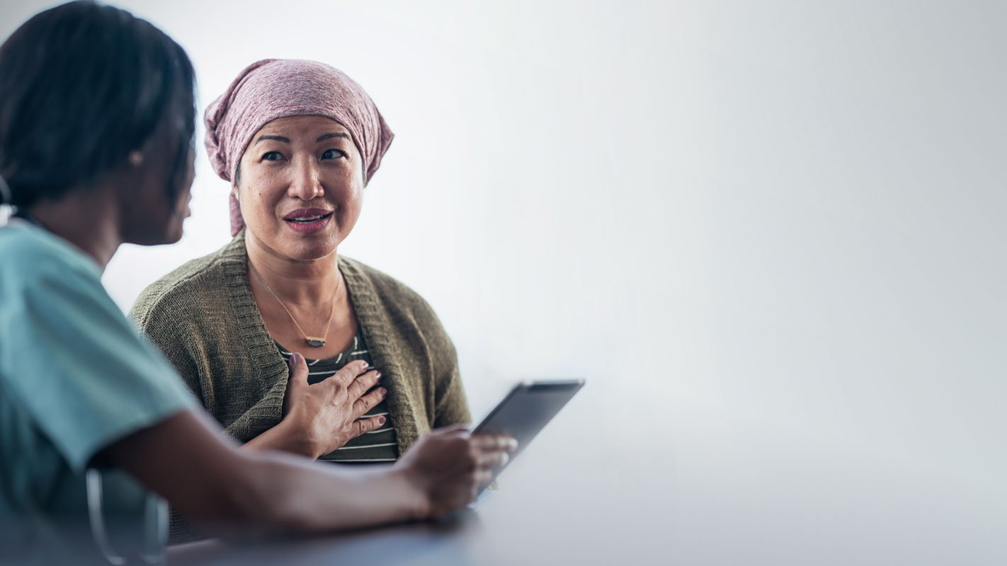 A healthcare worker shows an iPad to a cancer patient