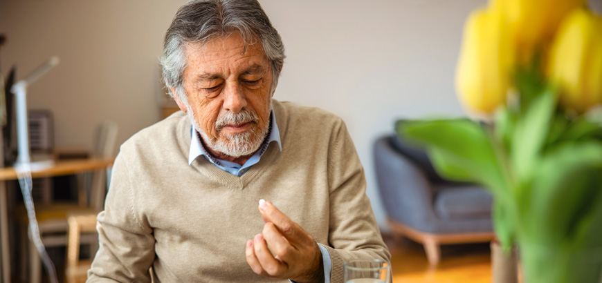 An older man taking medication with breakfast.