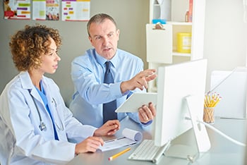 A doctor and hospital worker review information on a computer